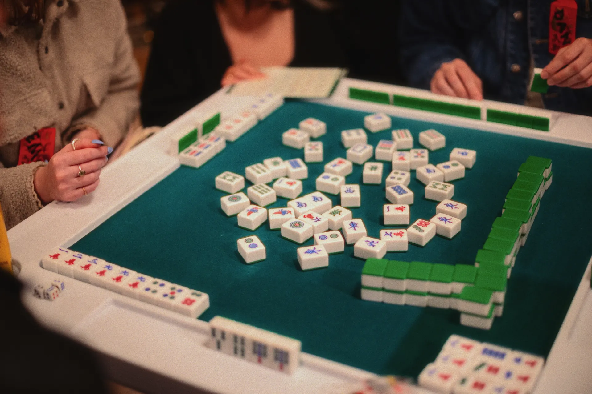 A group of people gathered around a table playing mahjong together